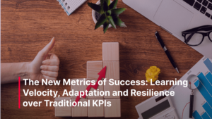 A workspace with a laptop, notebook, pen, plant, and wooden blocks stacked in steps with a red arrow pointing upward. A hand gives a thumbs-up beside the blocks, symbolizing growth and positive performance. The image represents progress, learning, and resilience in business metrics.